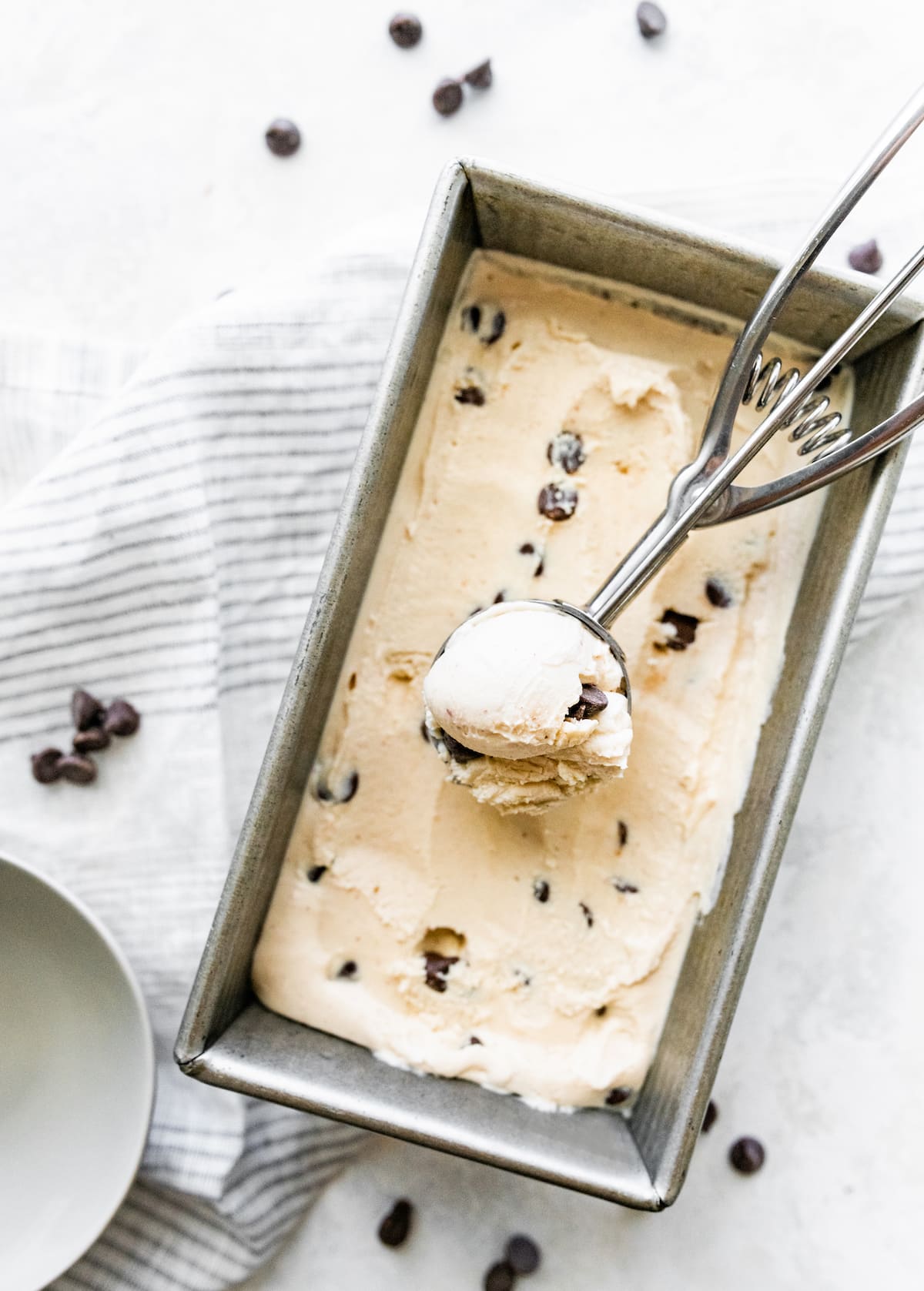 Ice cream scoop scooping cottage cheese ice cream from loaf pan.