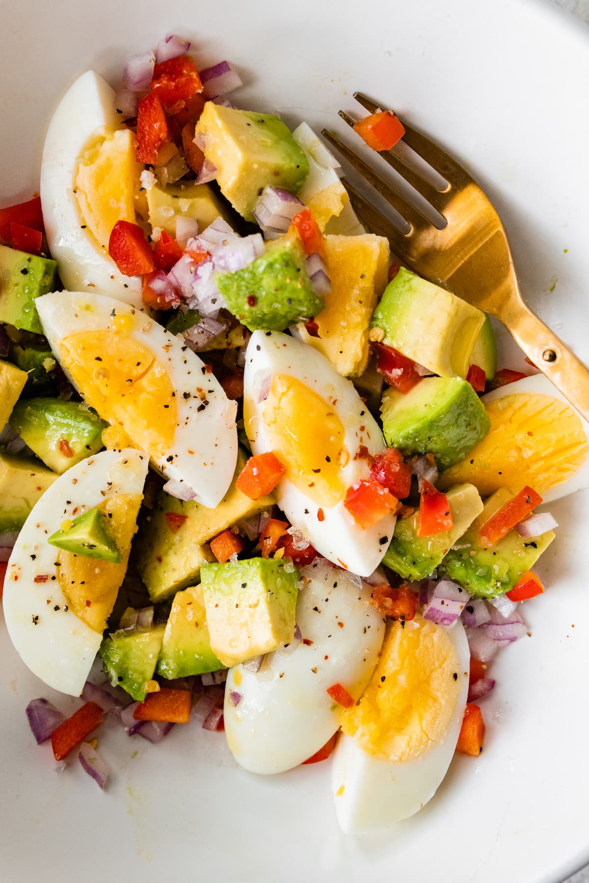 PIN THIS--> Egg and Avocado Bowl A bowl with hard boiled eggs, black pepper, onion, diced avocado, and red bell pepper.
