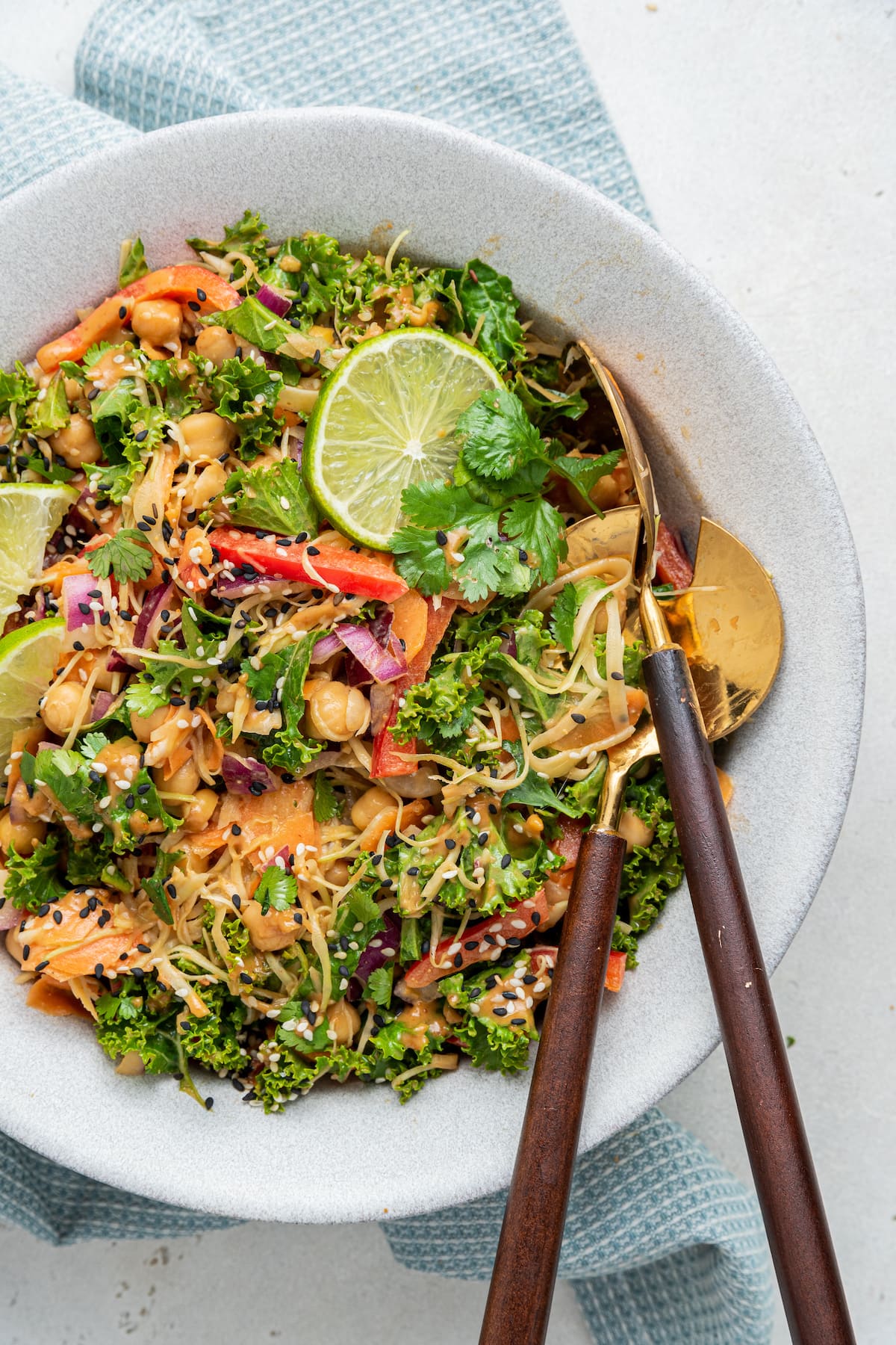 A serving of kale and cabbage pad Thai salad with a lime wedge on top.