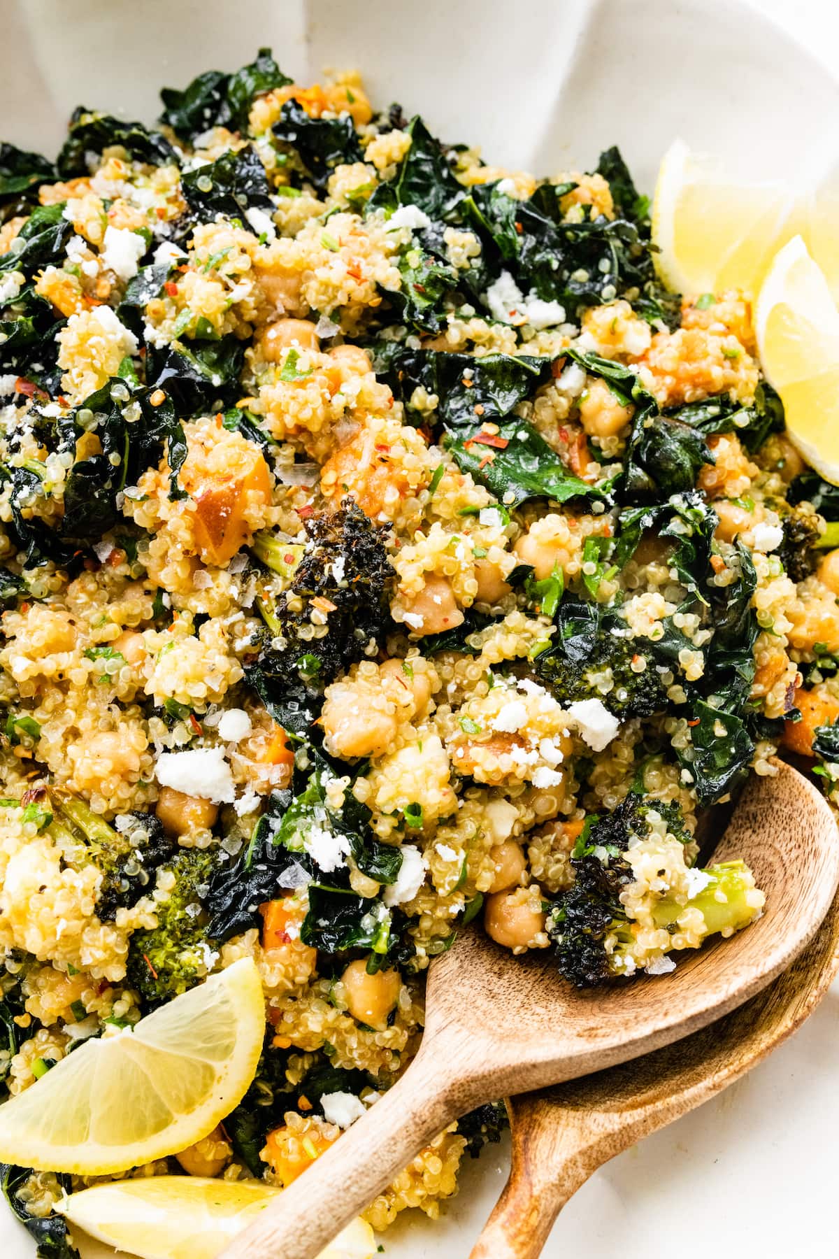 PIN THIS --> Roasted Broccoli Quinoa Salad Roasted broccoli quinoa salad in a large white bowl with two wooden serving spoons.