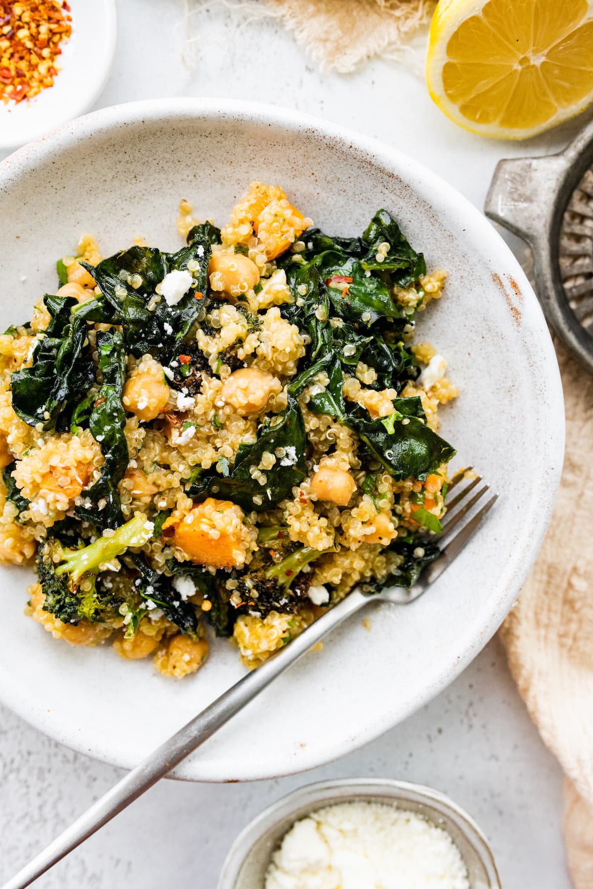 PIN THIS --> Roasted Broccoli Quinoa Salad A white plate with a metal fork and a roasted broccoli quinoa salad serving.