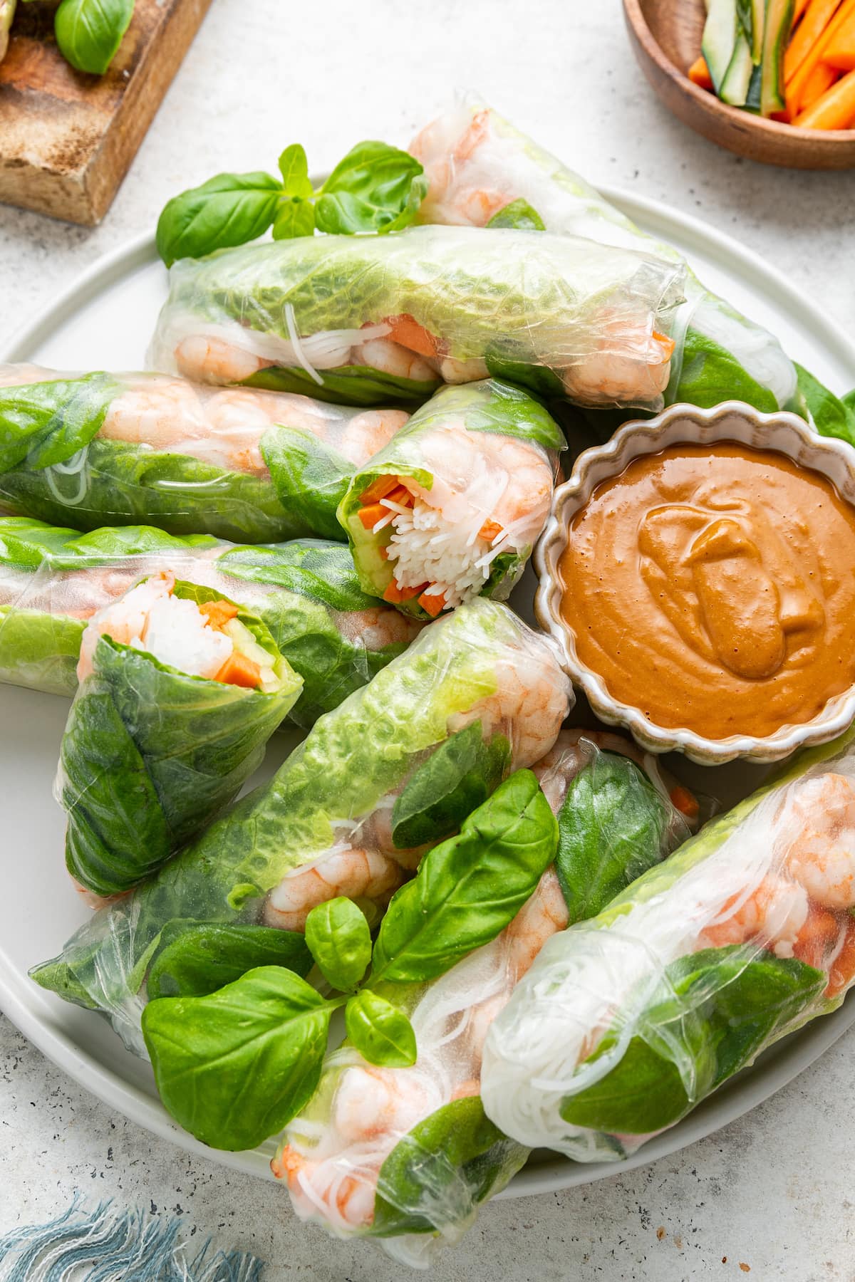 A serving of multiple fresh shrimp spring rolls with s small bowl of peanut sauce.