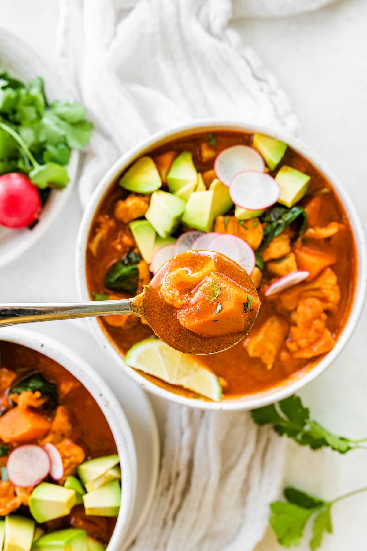 Mexican Sweet Potato Soup with Chicken, Cauliflower and Spinach // Gluten-free, Paleo and Whole30 approved A bowl of Mexican sweet potato chicken soup with a spoon over the top of the bowl as if someone was going to take a bite.
