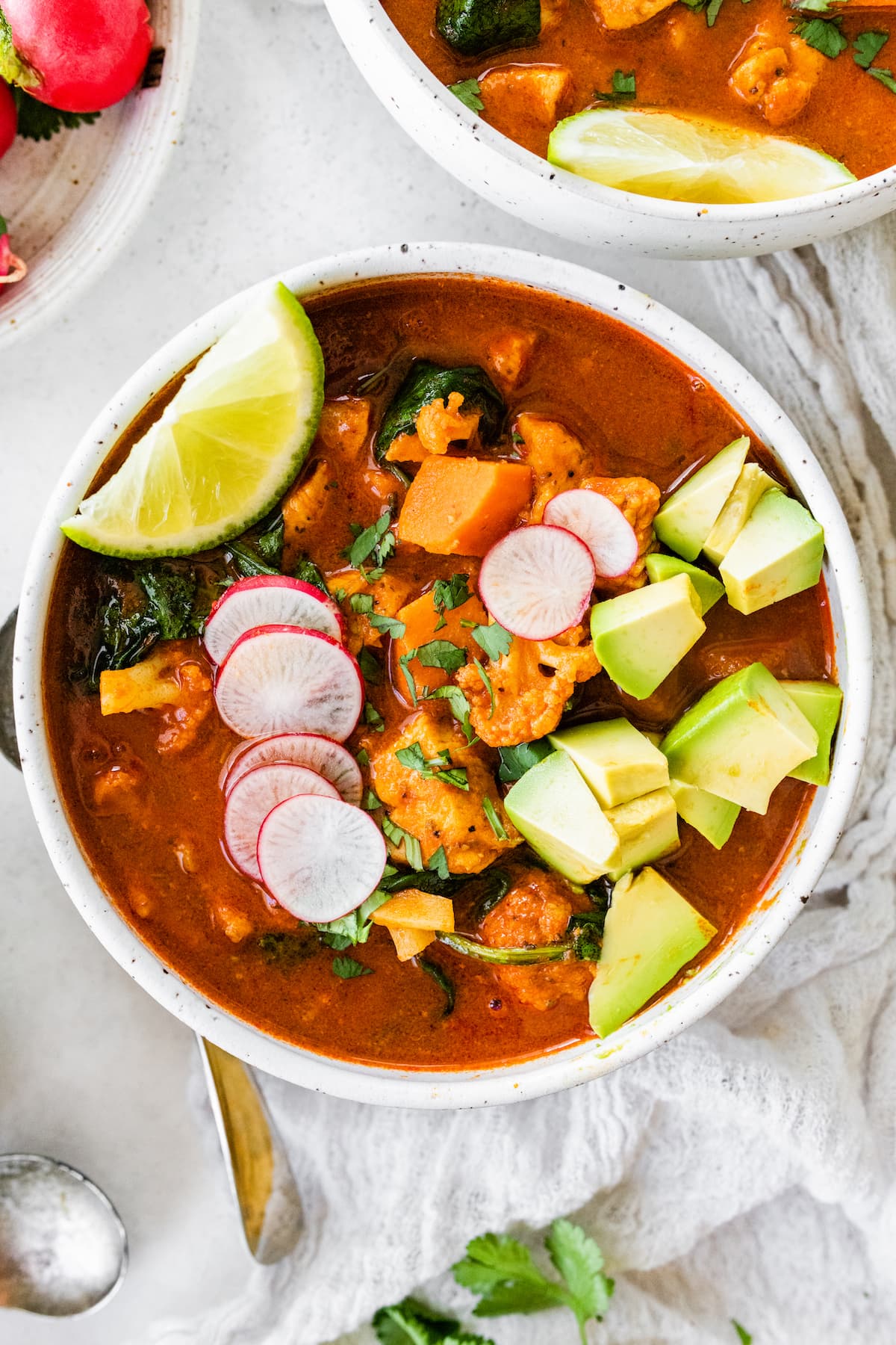 Mexican Sweet Potato Chicken Soup // Gluten-free, Paleo and Whole30 approved A bowl of Mexican sweet potato chicken soup topped with sliced radish, cilantro, avocado, and a lime wedge.