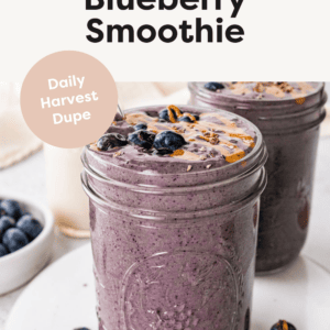 A chocolate blueberry smoothie in a mason jar topped with fresh blueberries and a drizzle of nut butter.