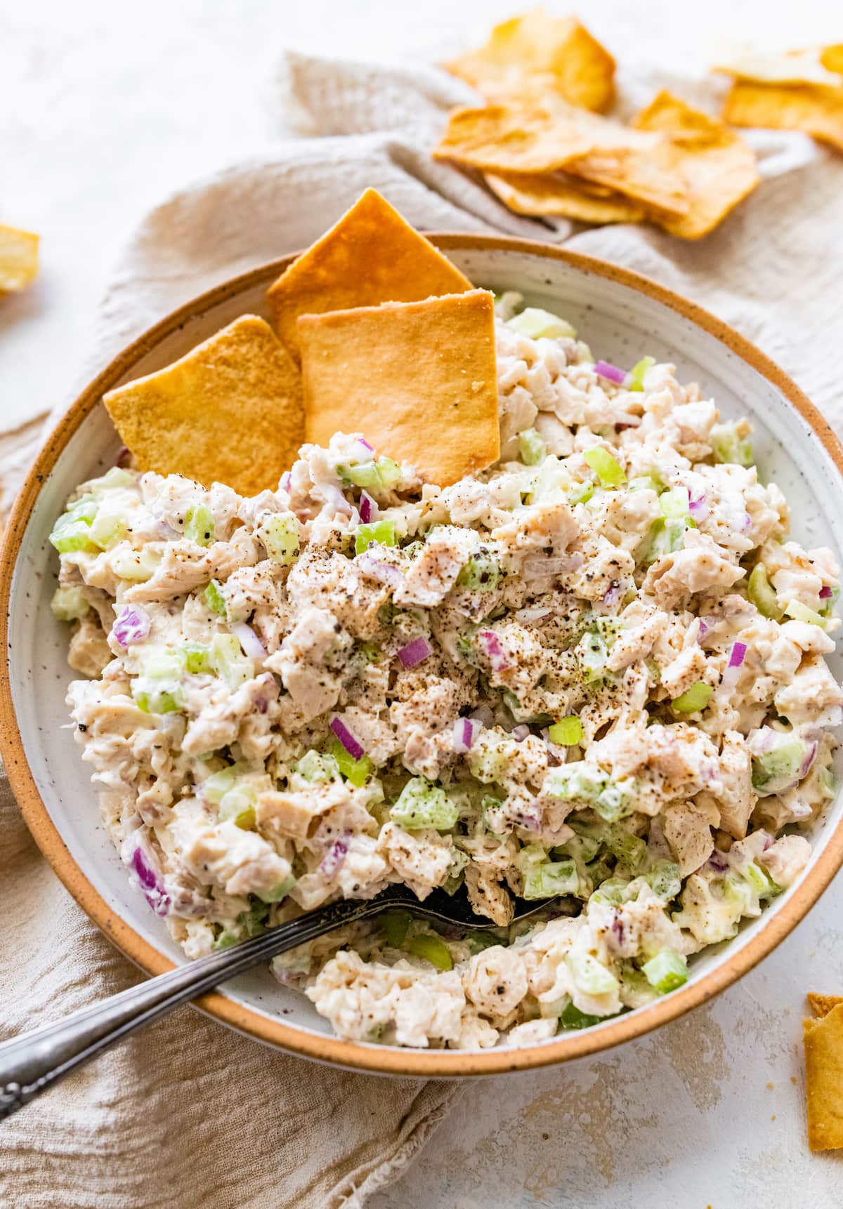 Rotisserie chicken salad in a bowl with a metal spoon and crackers.