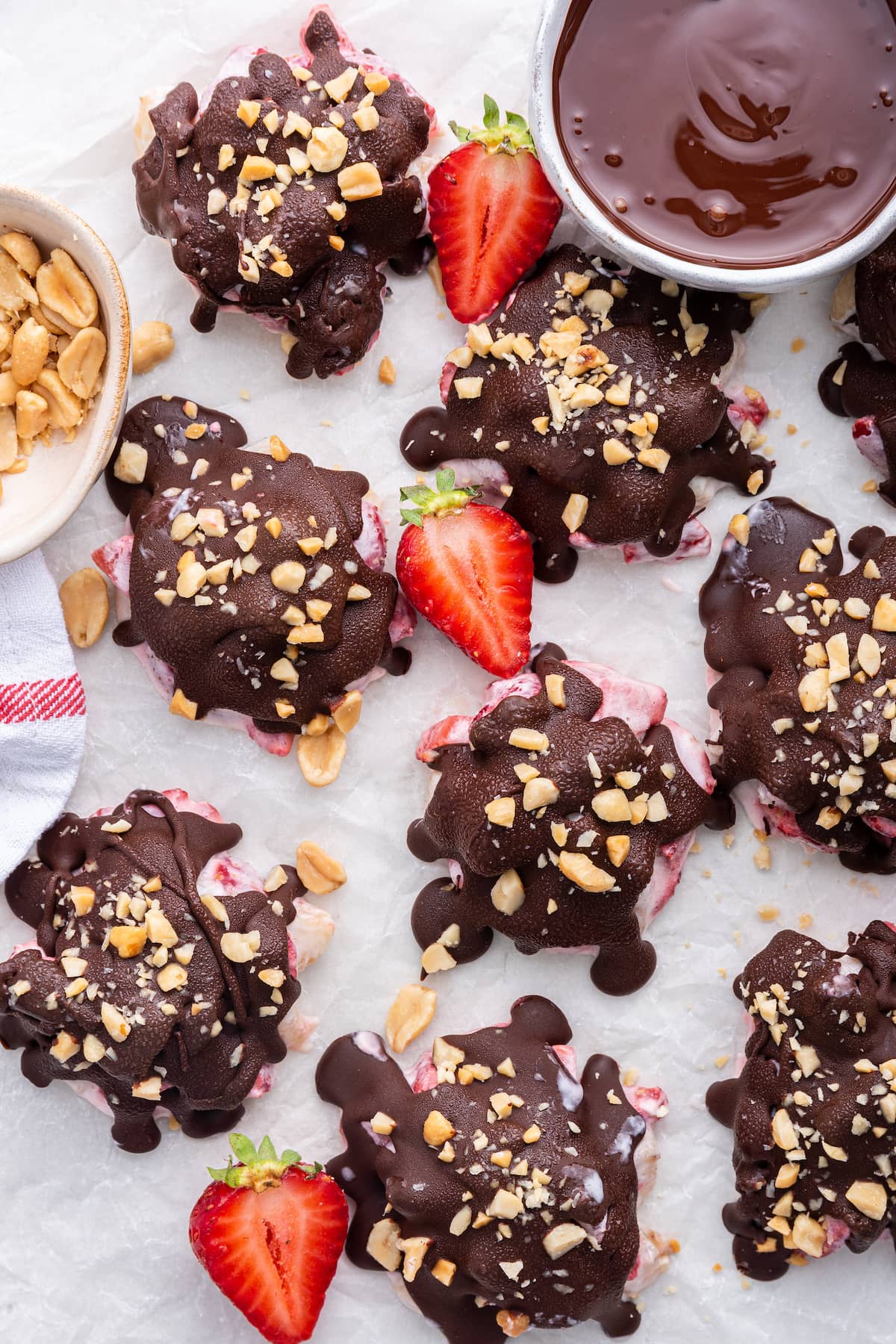 Chocolate strawberry banana yogurt clusters spread out on a piece of parchment paper.