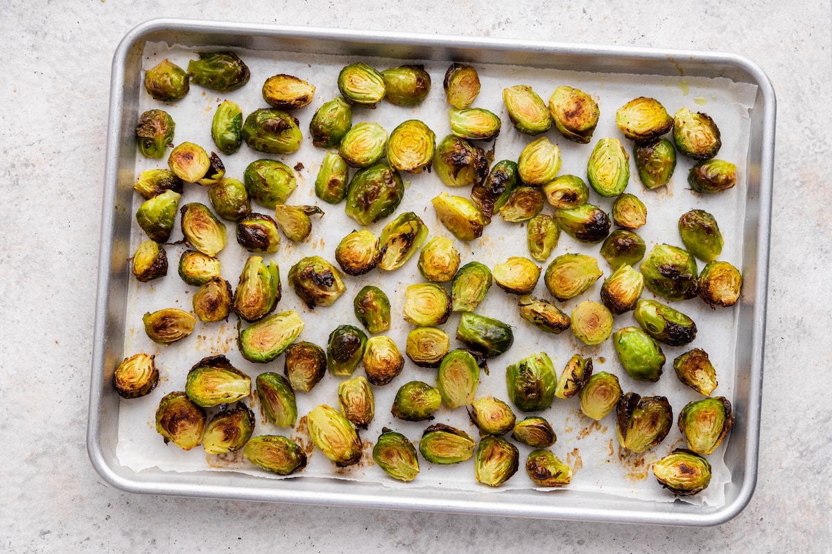 Roasted Brussels sprouts spread out on a baking sheet.
