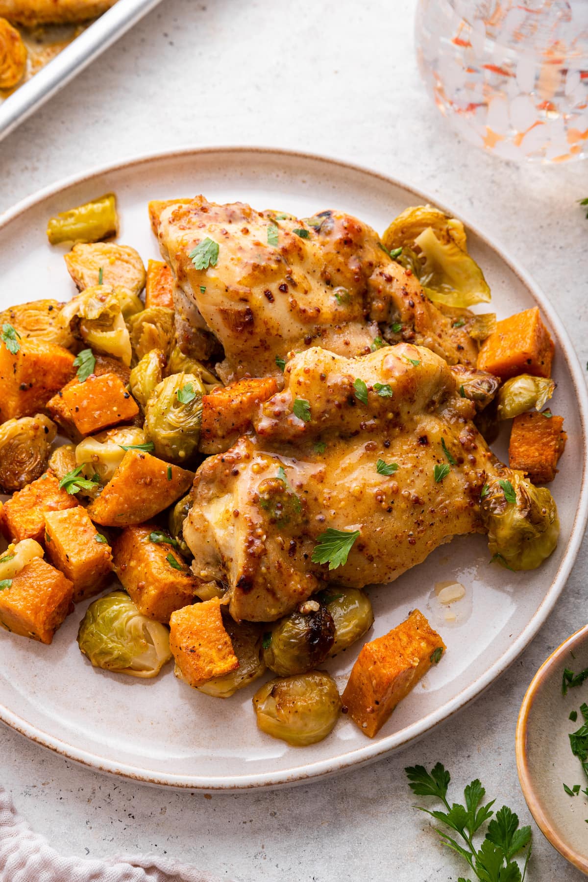 A serving of roasted honey mustard chicken with diced sweet potatoes, and Brussels sprouts.