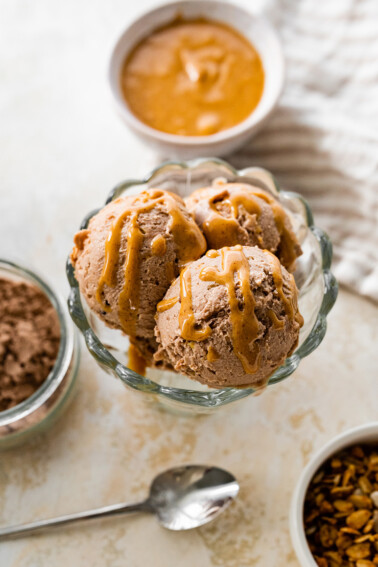 Chocolate peanut butter protein icee cream scooped in an ice cream bowl drizzled with peanut butter.