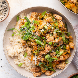 A serving of ground turkey with white rice garnished with sesame seeds and green onions.