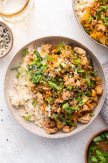 A serving of ground turkey with white rice garnished with sesame seeds and green onions.
