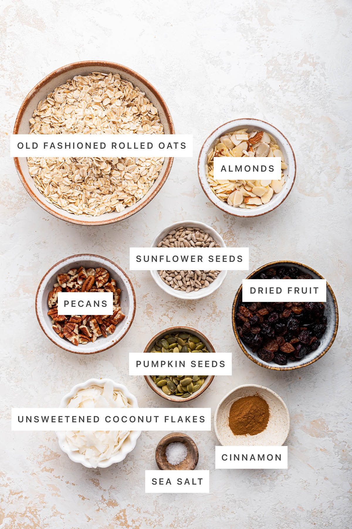 Ingredients measured out to make Muesli: oats, almond, sunflower seeds, dried fruit, pecans, pumpkin seeds, coconut flakes, sea salt and cinnamon.