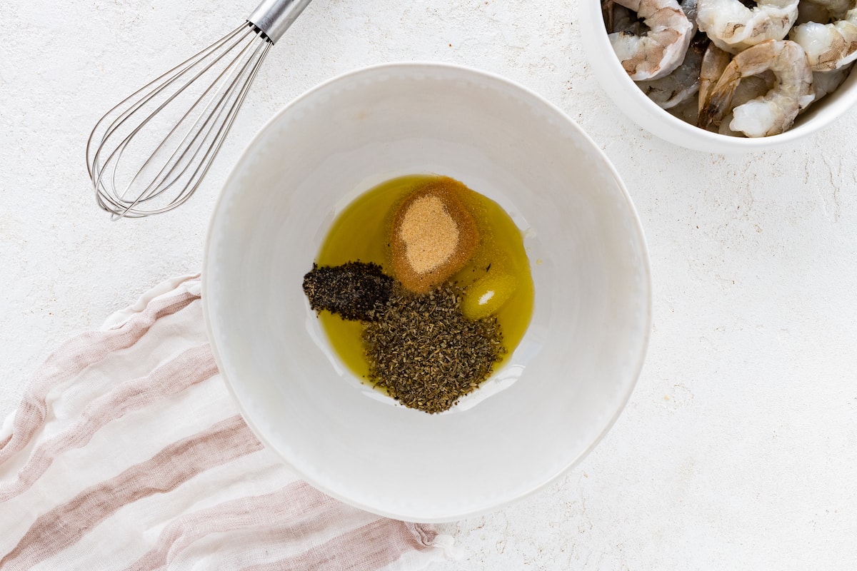 A large bowl with olive oil herbs and spices.