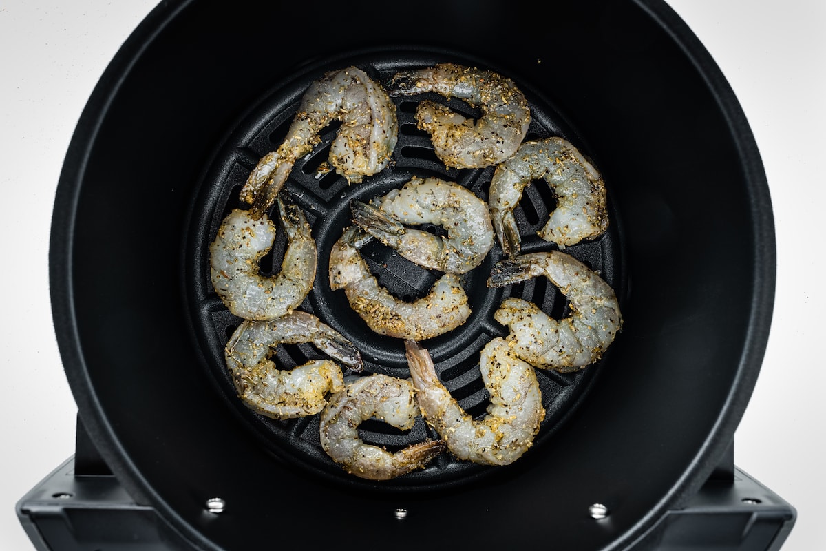 Raw shrimp in an air fryer basket.