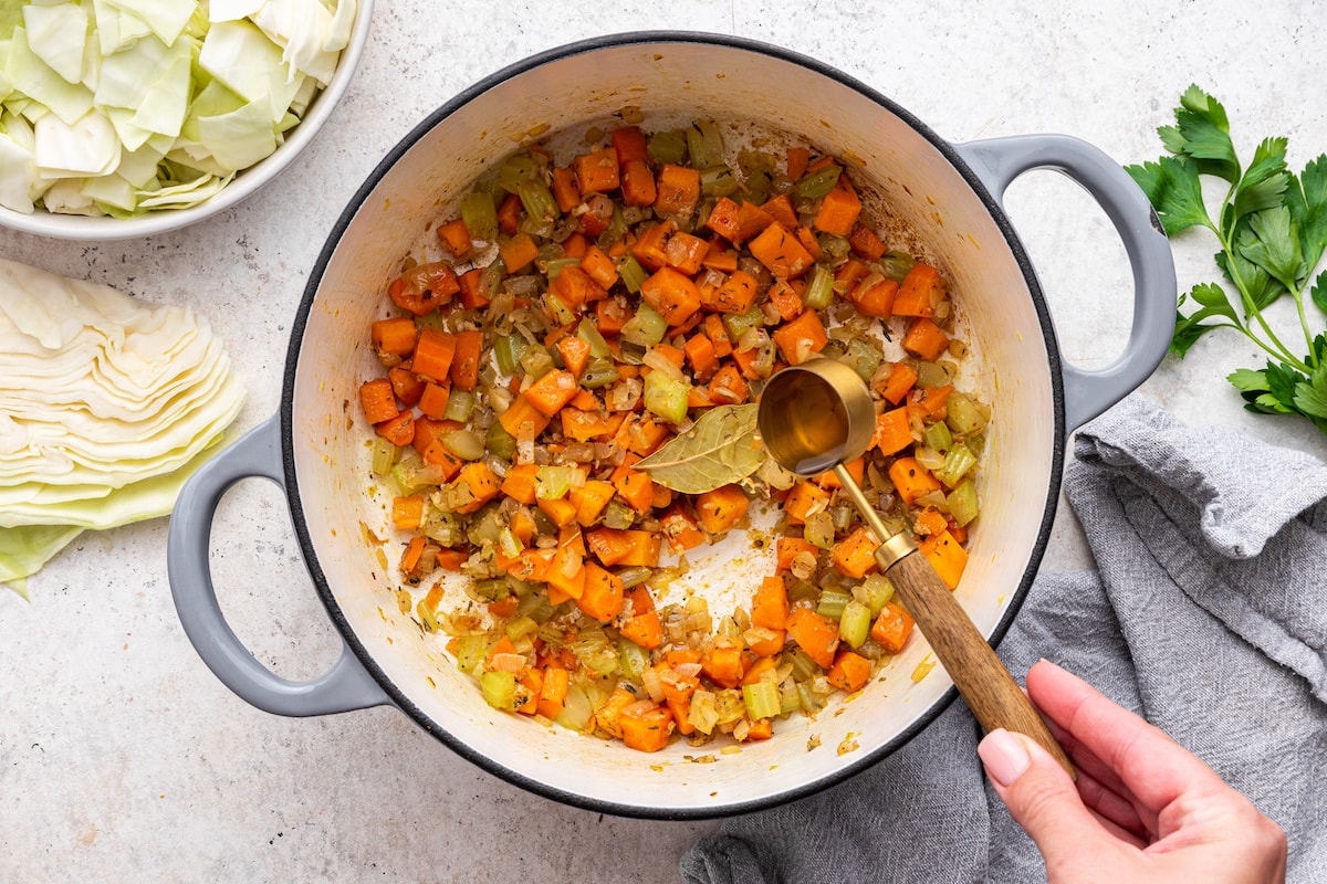 A tablespoon of vinegar is added to a large pot of diced vegetables.