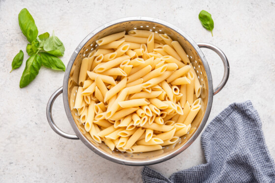 Penne pasta in a metal colander.