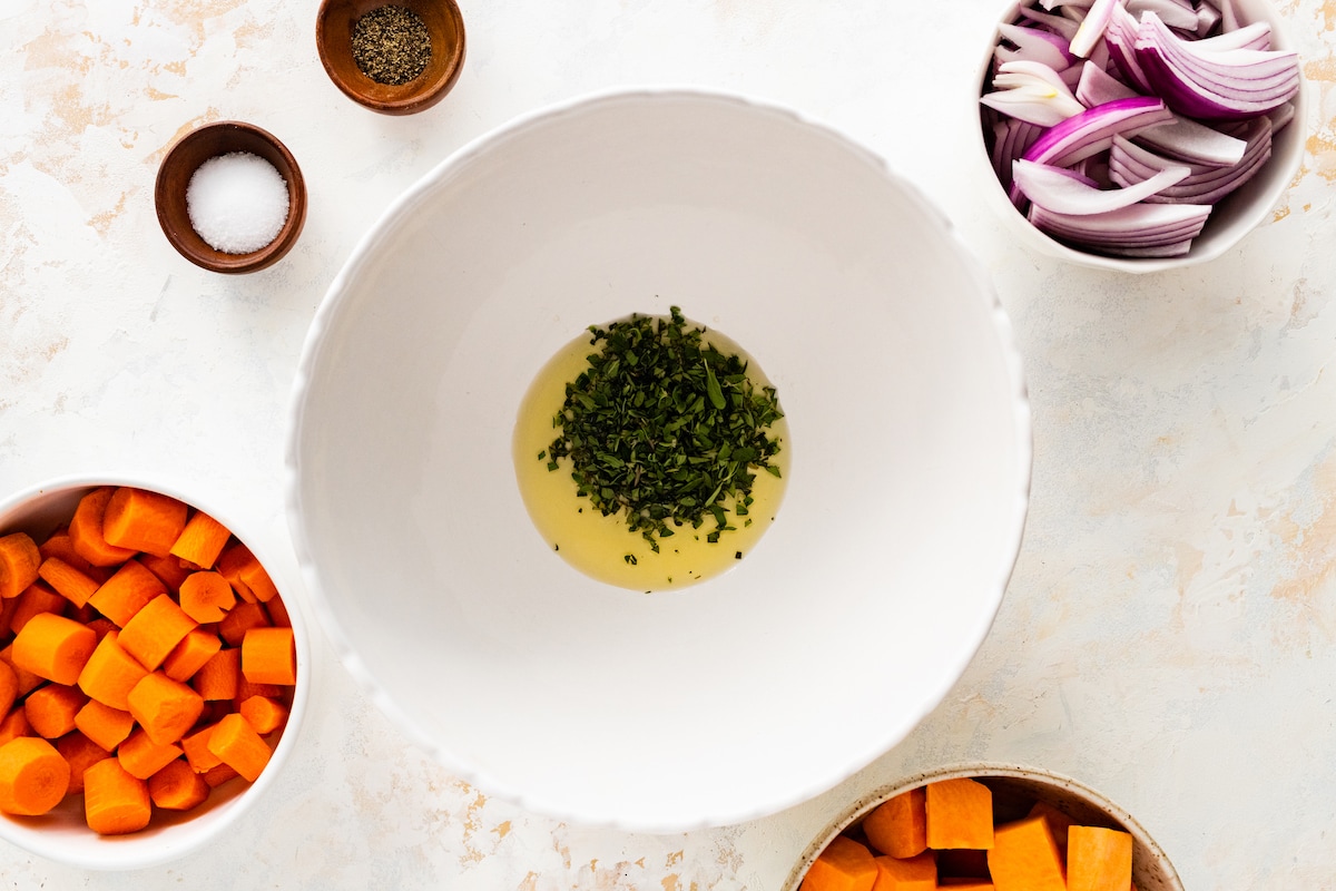 Fresh herbs and oil in a large mixing bowl.