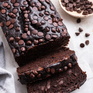 A loaf of chocolate banana bread with two slices cut.