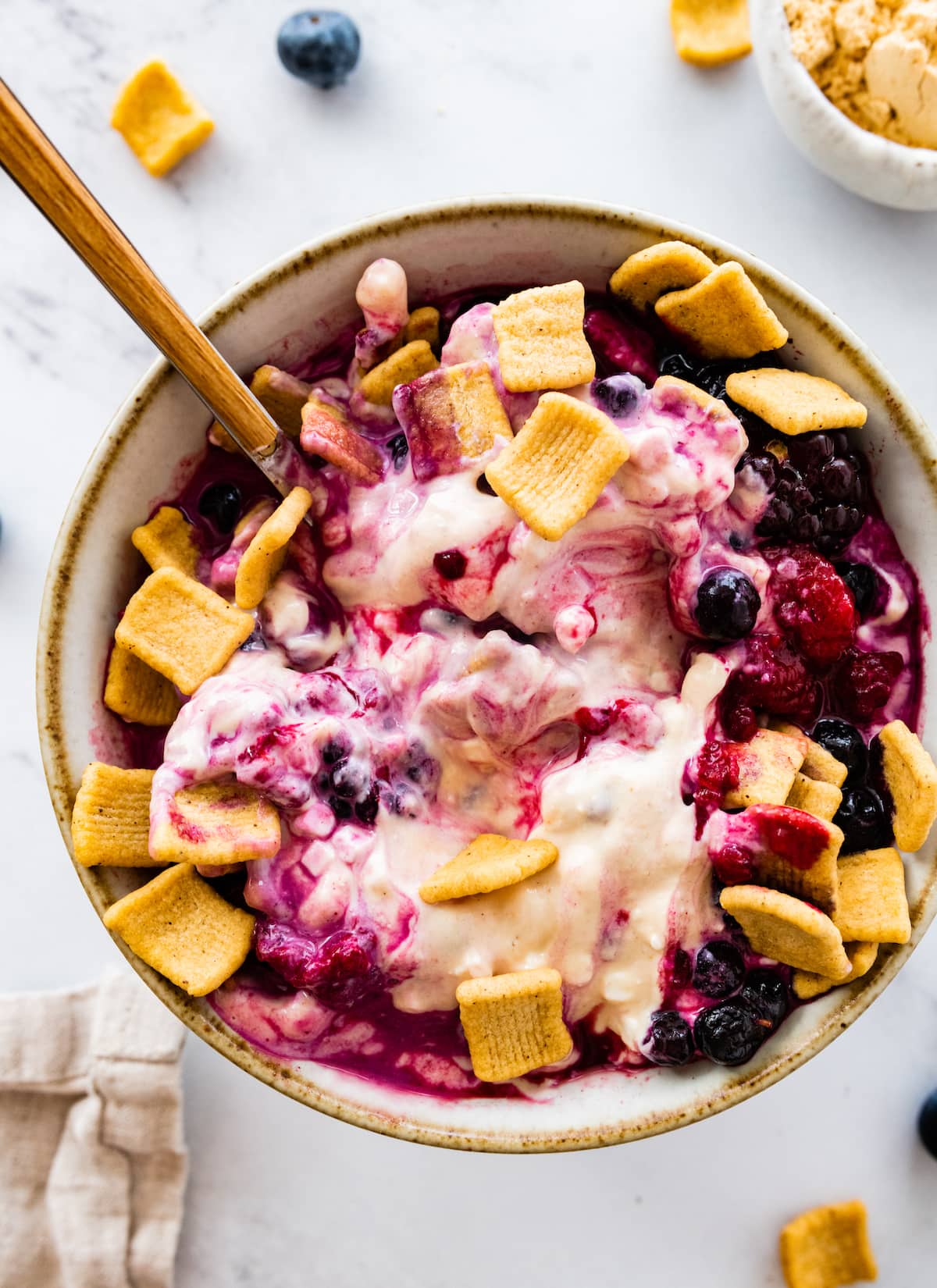 A peanut butter and jelly yogurt bowl topped with crunchy cereal and fresh berries.
