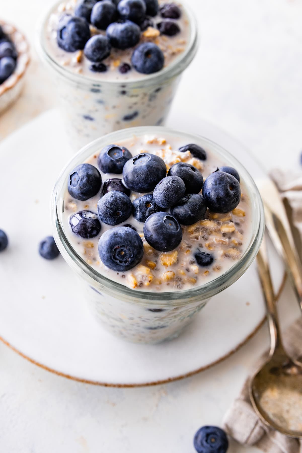 A serving of blueberry overnight oats in a glass jar topped with fresh blueberries.