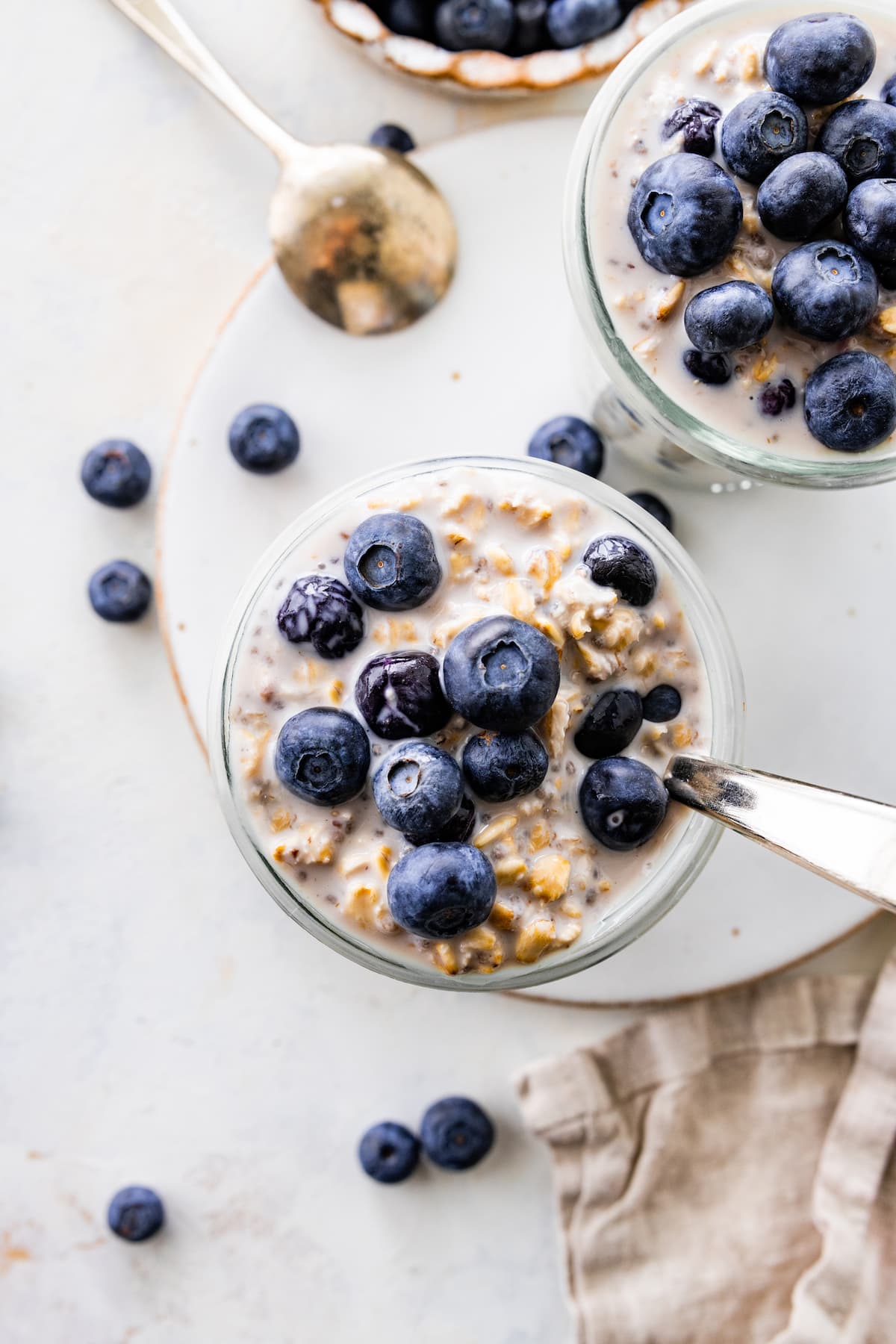 Blueberry overnight oats in a glass cup served with fresh blueberries on top.