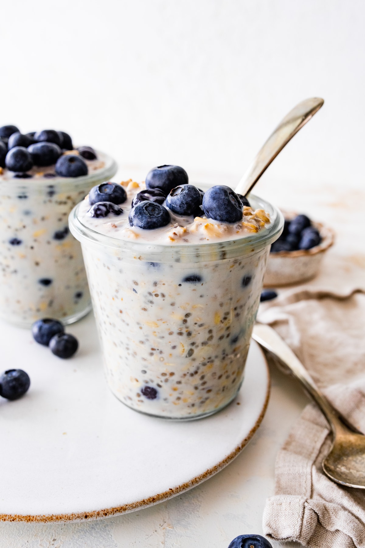Two glass jars with blueberry overnight oats topped with fresh blueberries.