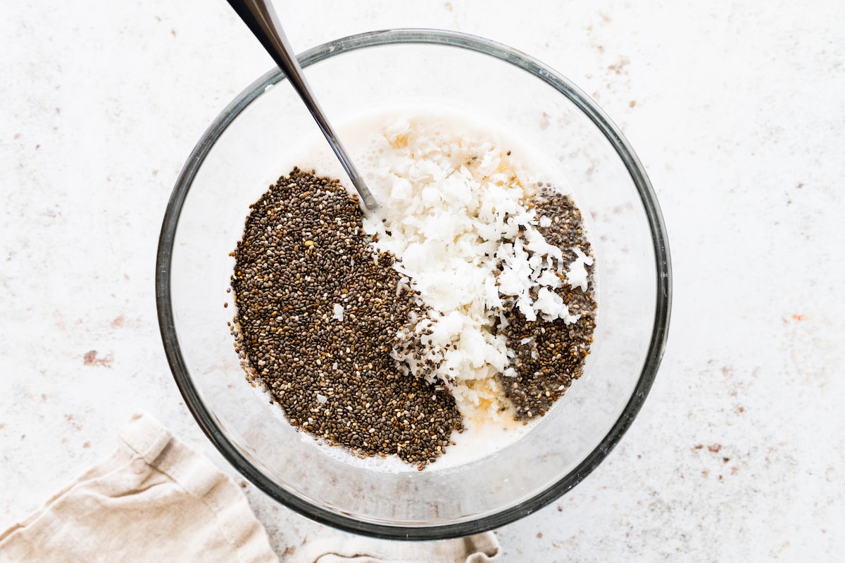Chia seeds, milk, and coconut shreds in a glass bowl.