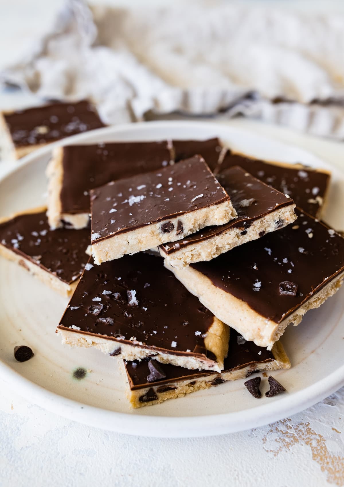 Protein cookie dough bark topped with flaked sea salt angled on a plate.