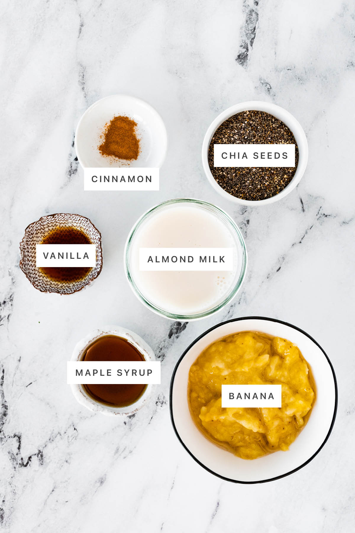 Ingredients measured out to make Banana Chia Pudding: cinnamon, chia seeds, vanilla, almond milk, maple syrup and banana.