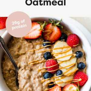 Bowl of Protein Oatmeal topped with berries and peanut butter. Spoon is in the bowl.