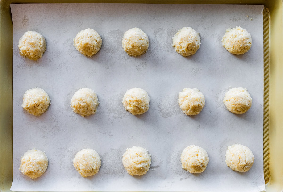 Coconut macaroon balls before being baked on a baking tray.