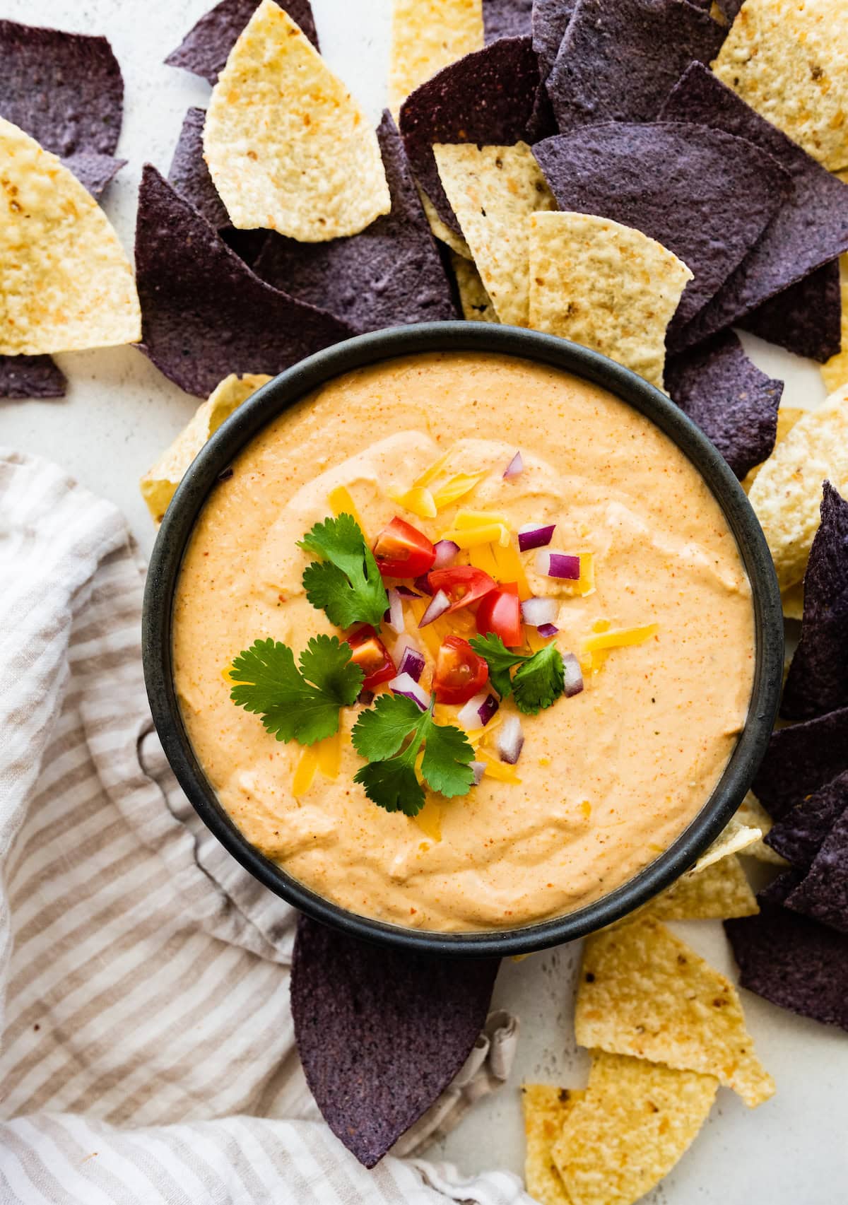 A serving of cottage cheese queso in a bowl near multiple tortilla chips.