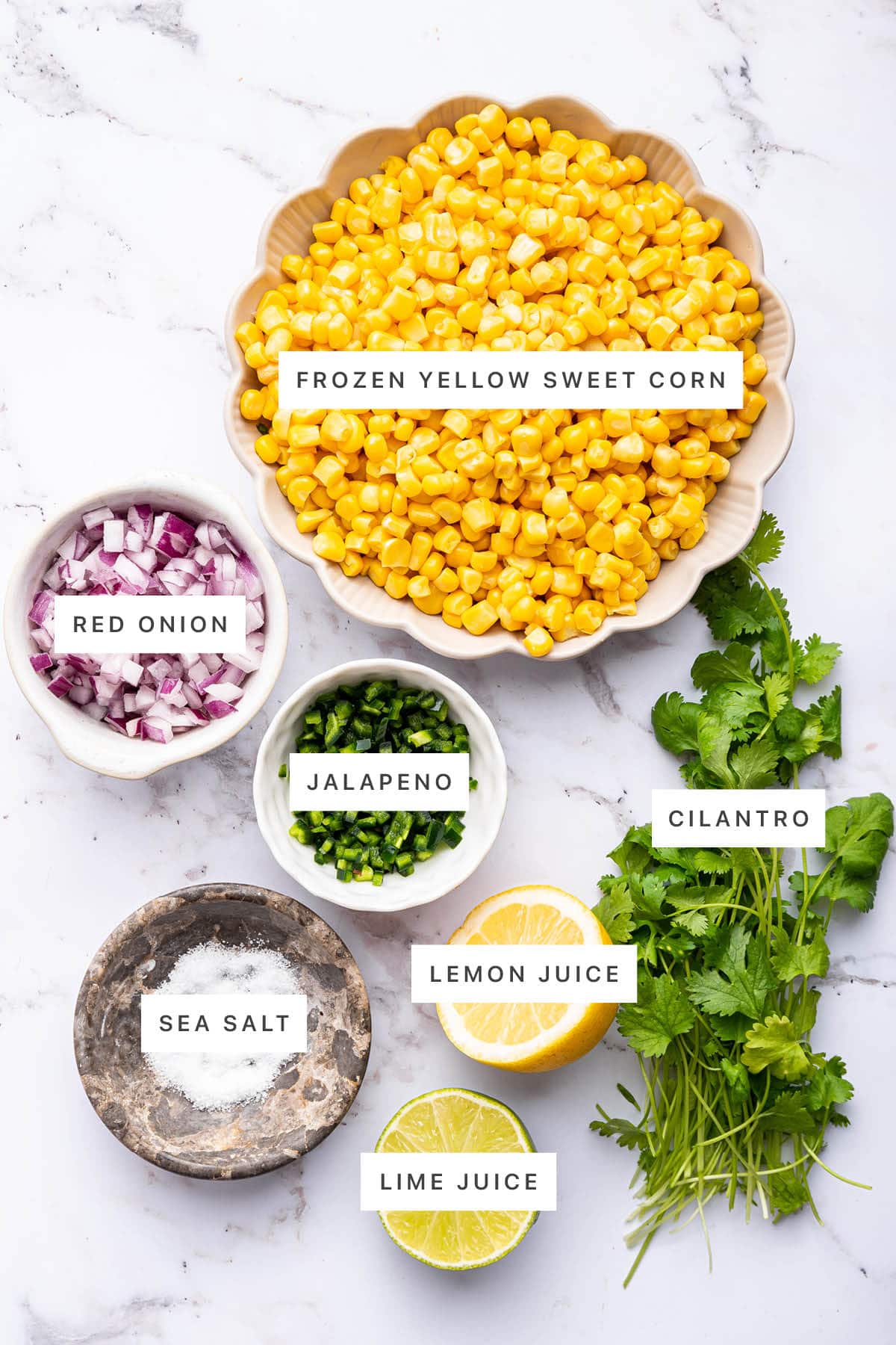 Ingredients measured out to make Easy Corn Salsa: frozen yellow sweet corn, red onion, jalapeno, cilantro, sea salt, lemon juice and lime juice.