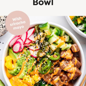 Photo of a Poke Bowl with sushi, sriracha mayo, avocado, mango, green onions, seaweed salad and sesame seeds.