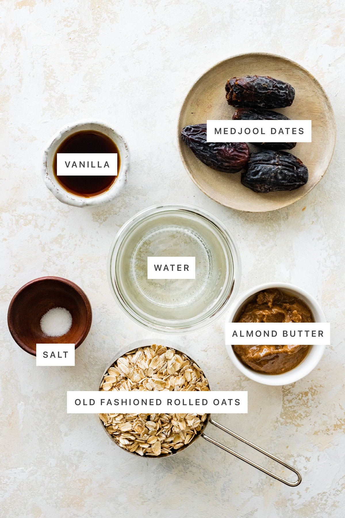 Ingredients measured out to make Vanilla Overnight Oats: vanilla, medjool dates, water, salt, almond butter and oats.