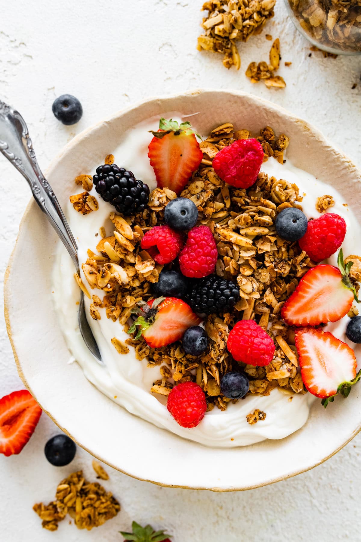 A small bowl of yogurt topped with coconut granola and fresh berries.
