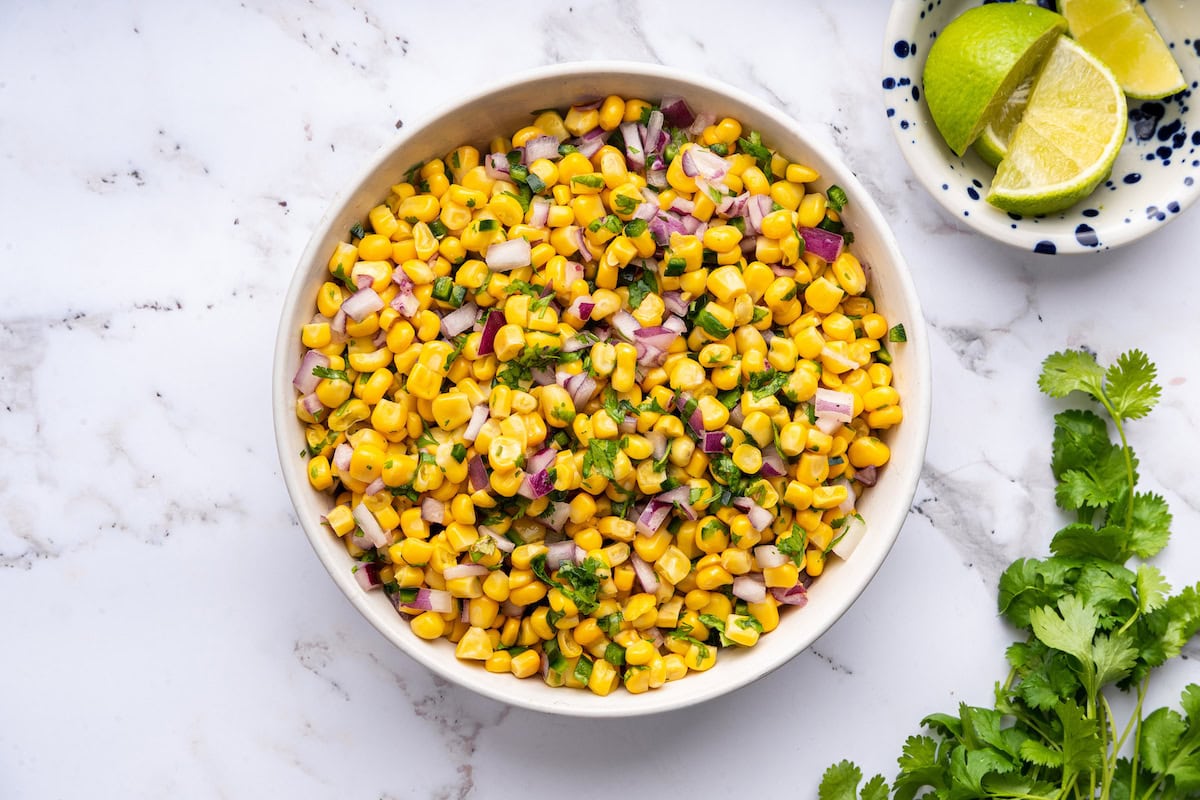 Ingredients for the corn salsa all mixed together in a white serving bowl.
