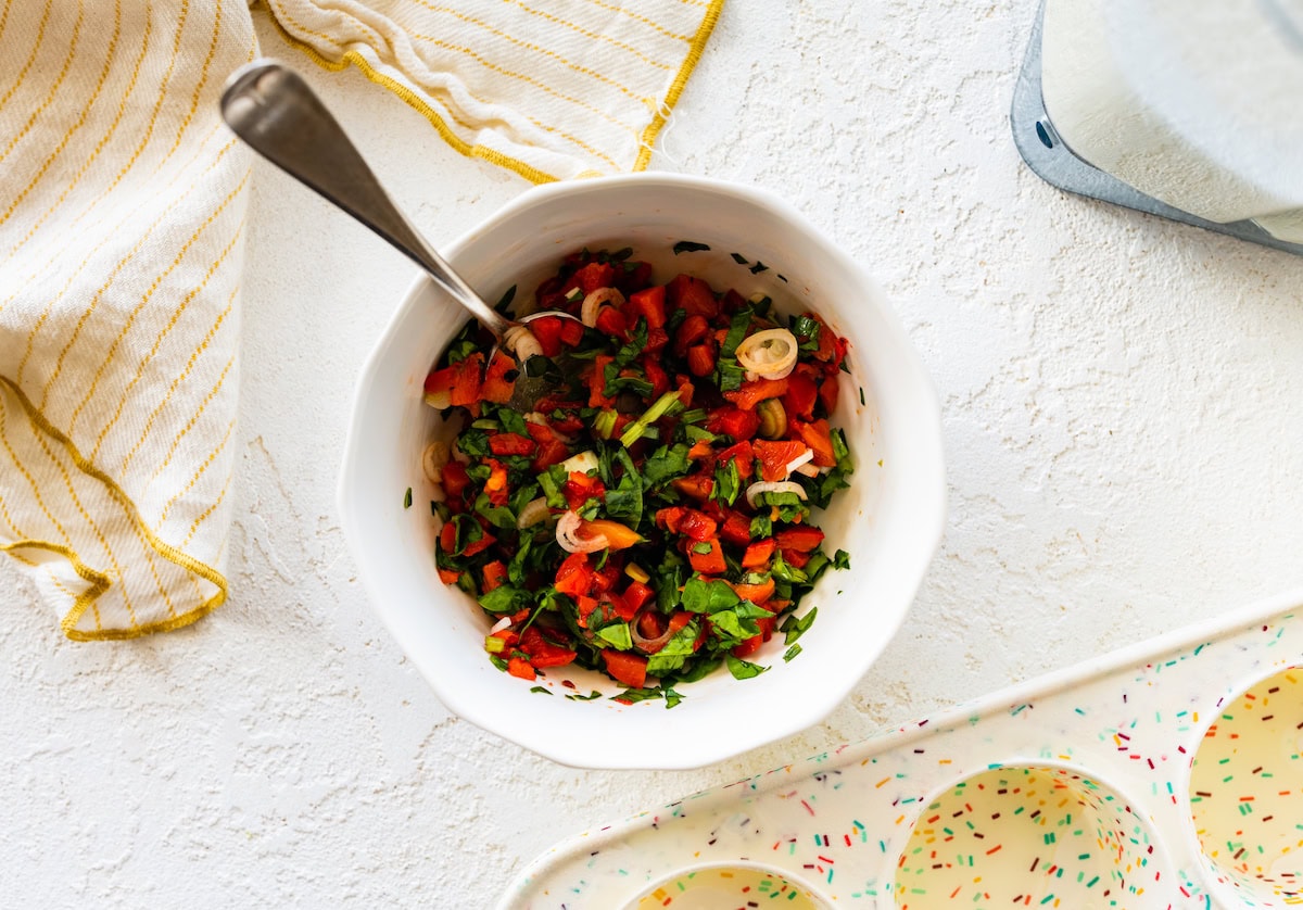 A mix of chopped red pepper, onion, and spinach in a small bowl.