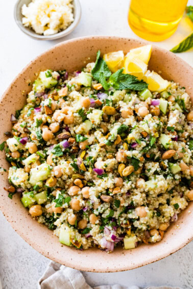 A salad inspired by Jennifer Aniston in a large bowl with quinoa, chickpeas, fresh herbs, and vegetables.