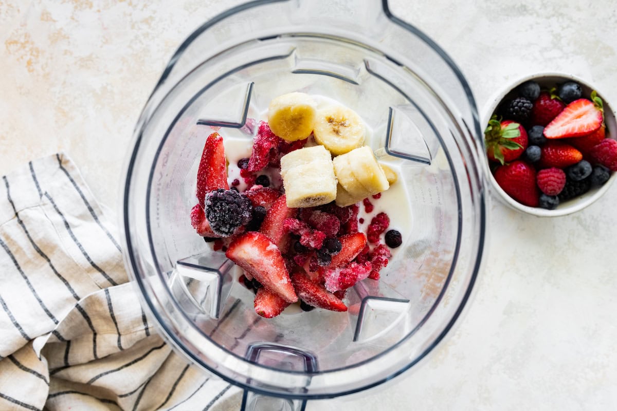Ingredients for the berry kefir smoothie in the base of a blender before being blended.