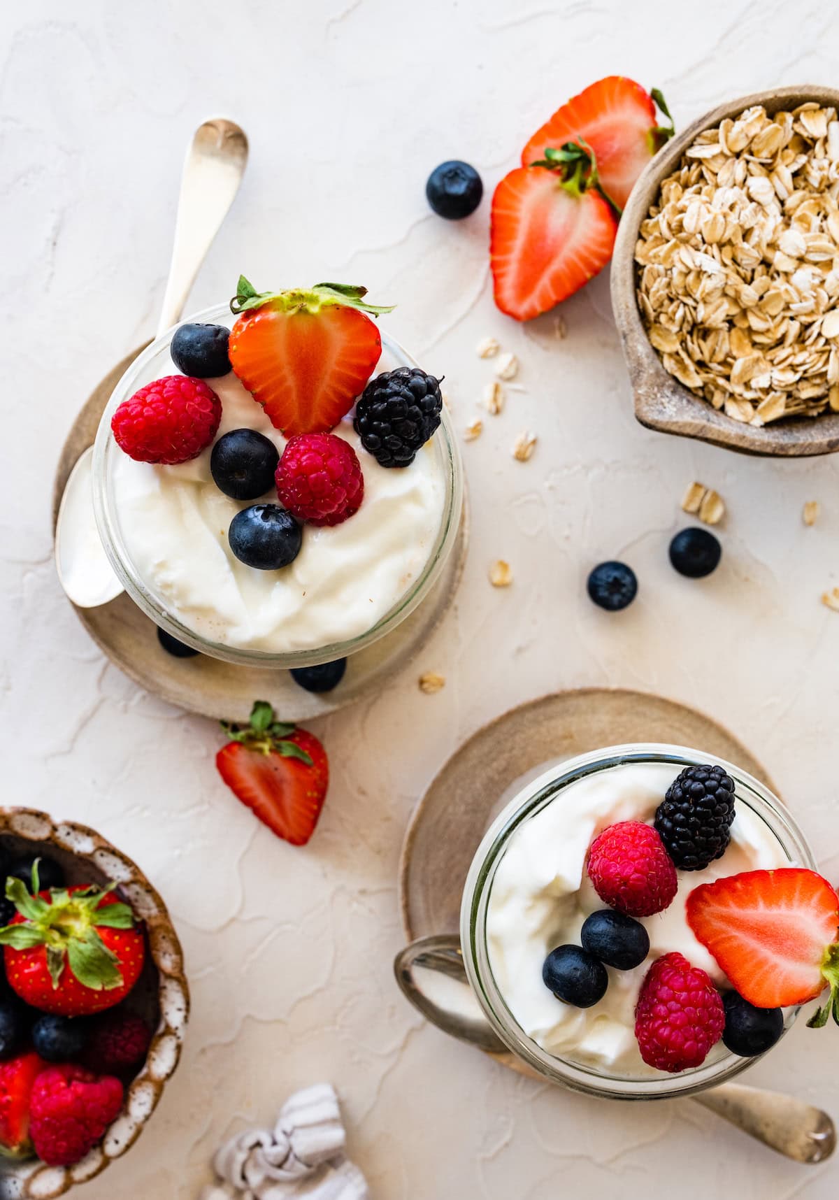Two glass cups with overnight oats containing yogurt are topped with fresh berries.