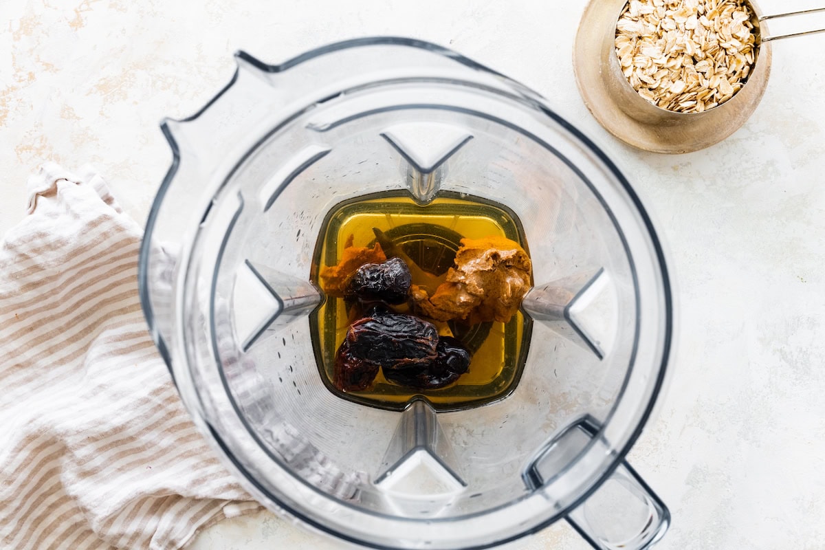 Dates, almond butter, and vanilla in a blender before being blended.