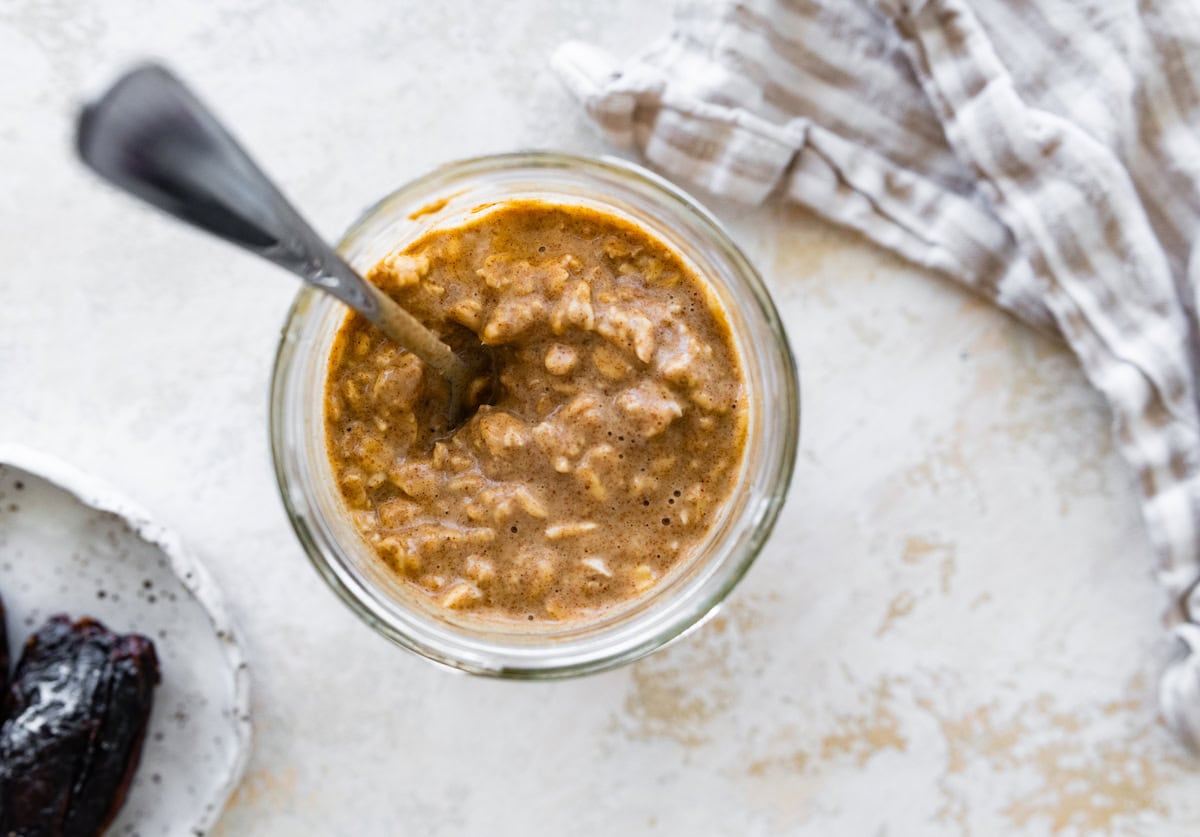 Vanilla overnight oats in a glass cup with a metal spoon.