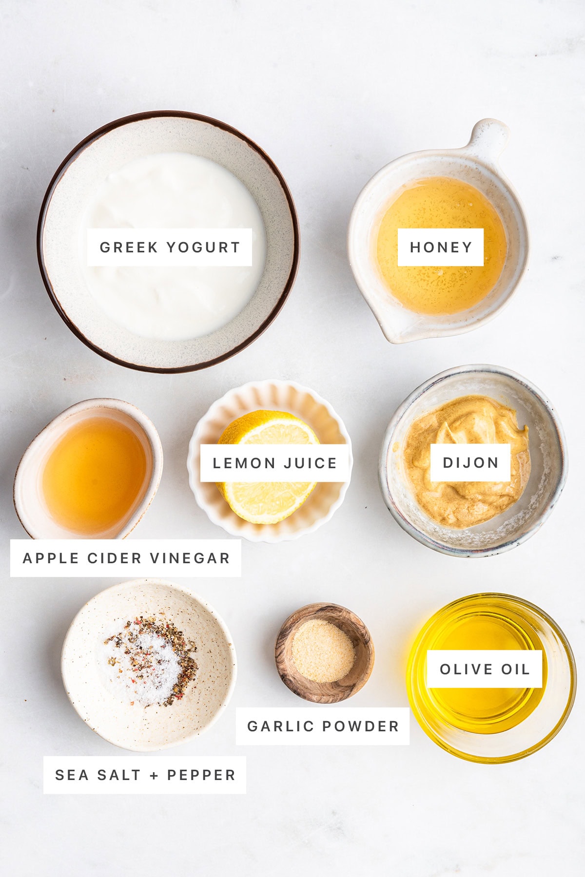 Ingredients used in a honey mustard dressing that includes: greek yogurt, honey, dijon mustard, lemon juice, vinegar, salt, pepper, garlic powder, and olive oil