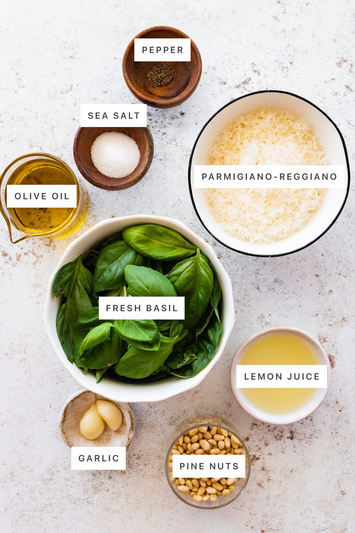 Ingredients measured out to make pesto: pepper, sea salt, olive oil, parmigiano-reggino, fresh basil, lemon juice, garlic and pine nuts.