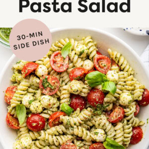 Pesto Pasta Salad with mozzarella and cherry tomatoes in a bowl.