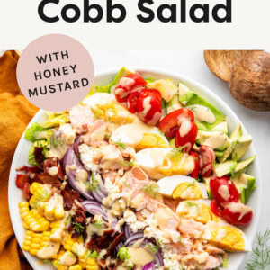 Salmon Cobb Salad in a serving bowl drizzled with honey mustard.