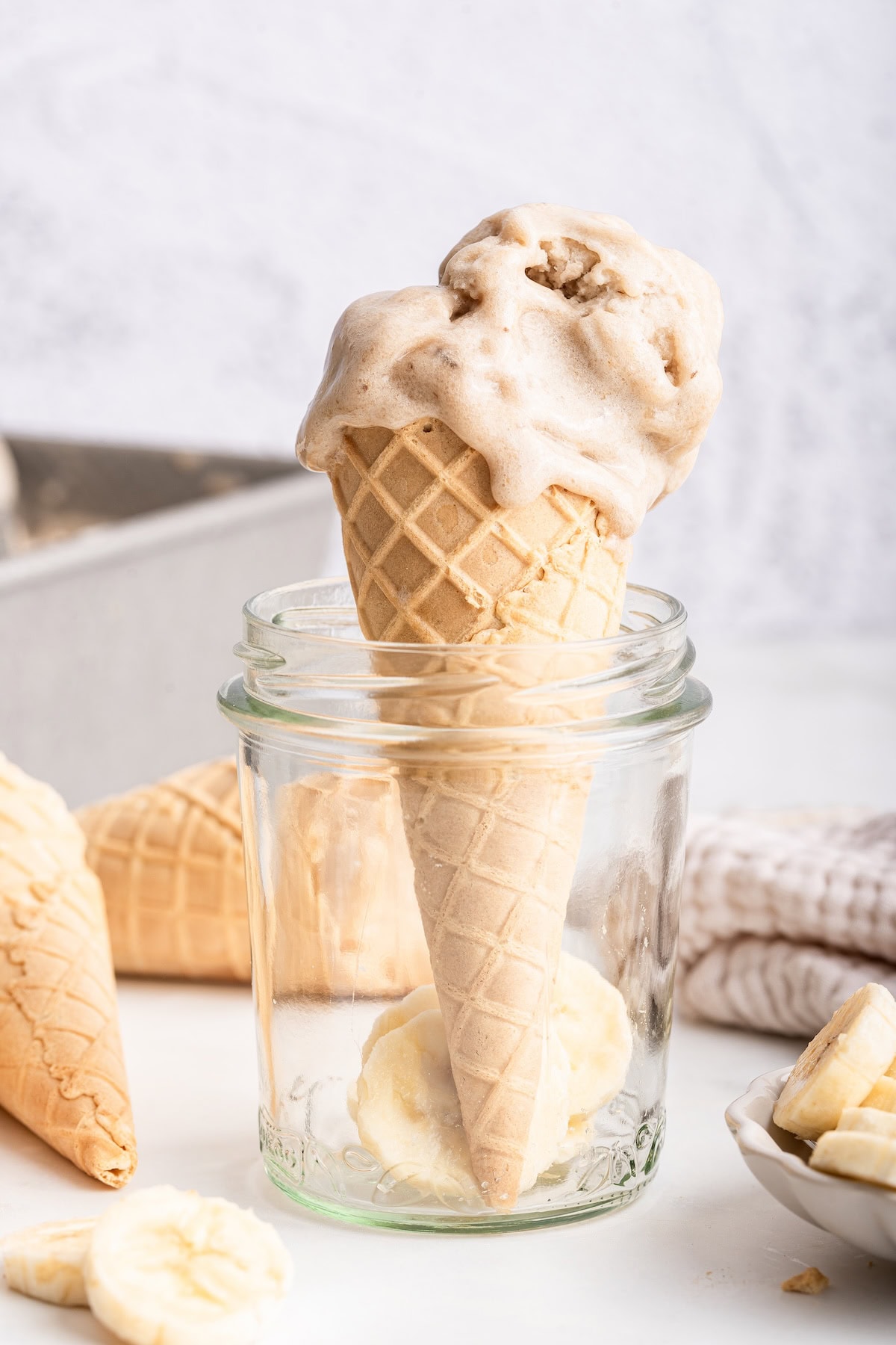 A waffle cone of banana ice cream standing up in a mason jar.