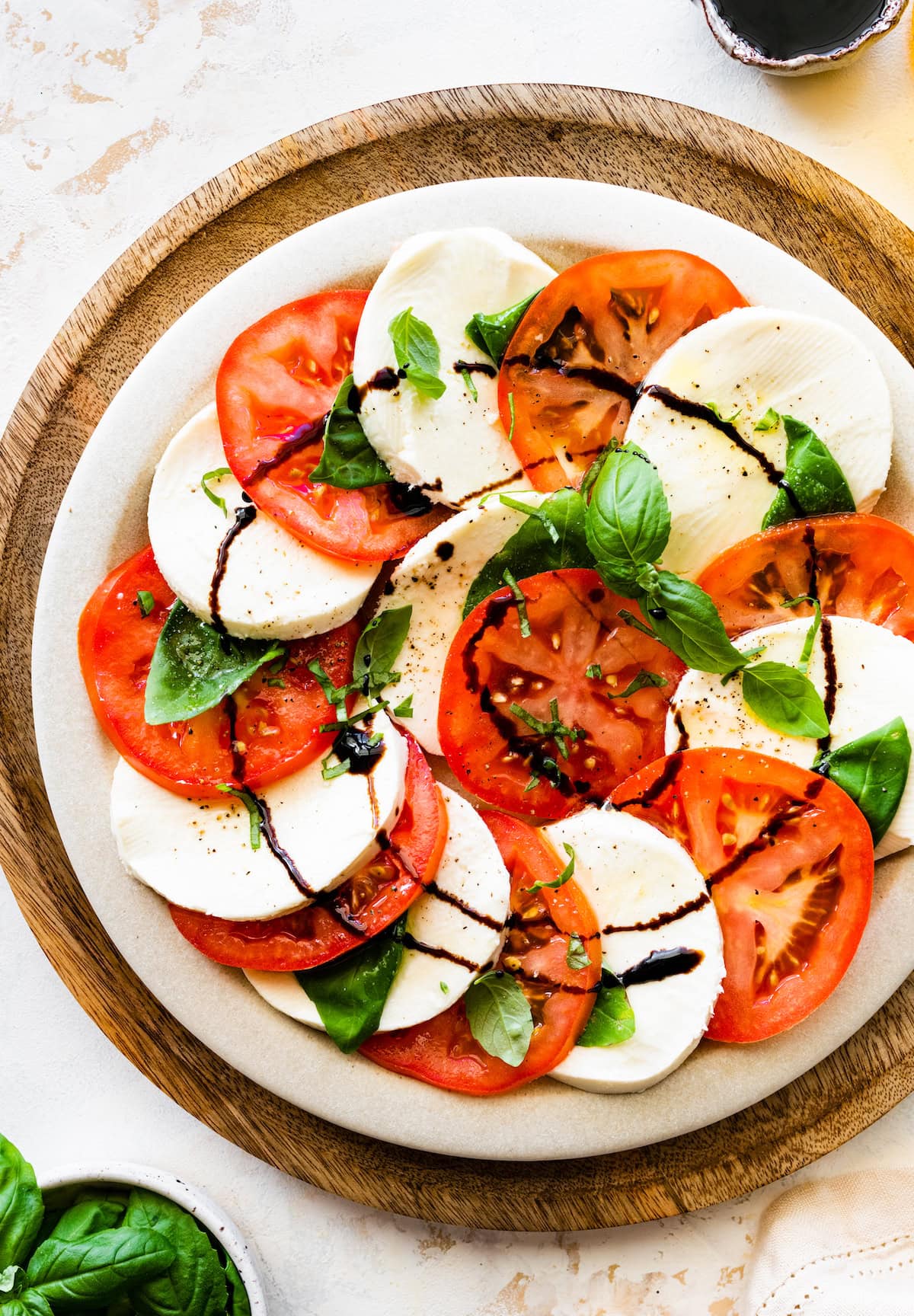 A serving of caprese salad with sliced tomatoes, mozzarella, fresh basil, and a drizzle of balsamic vinegar.